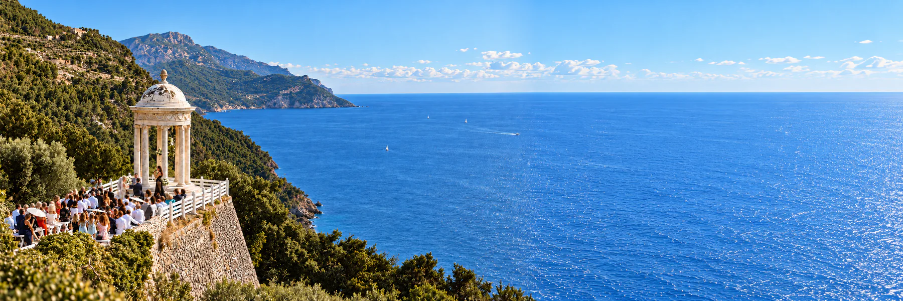 Wide coastal wedding scene at Son Marroig with the pavilion, wedding guests, Mediterranean sea and blue sky